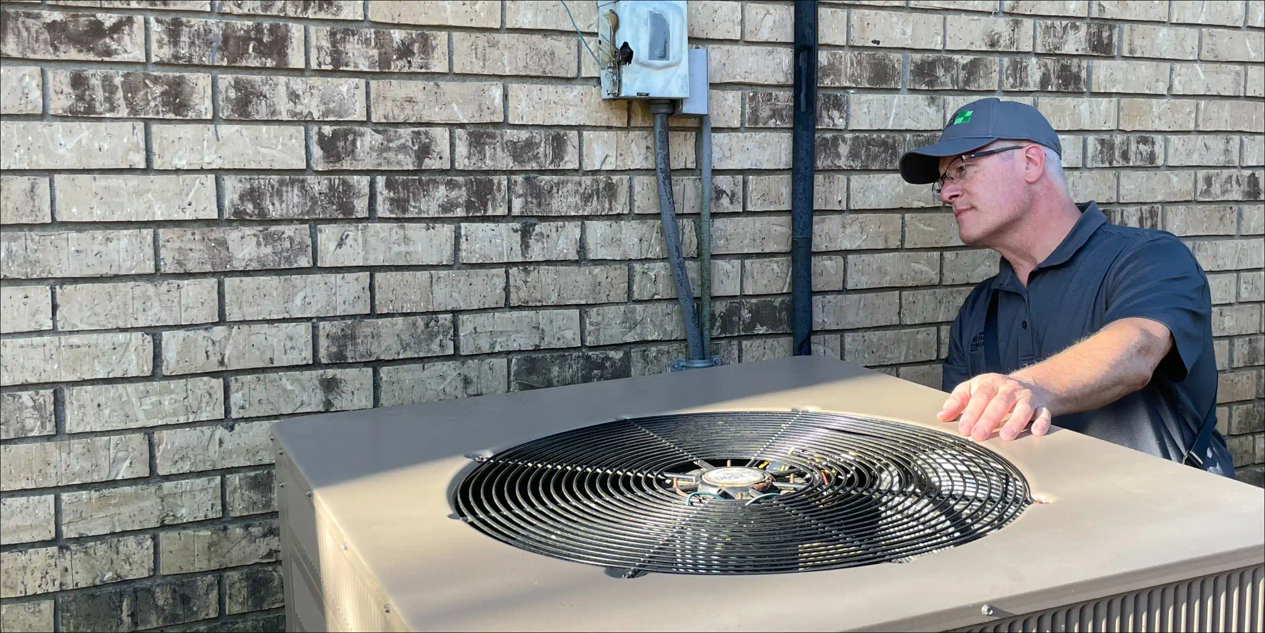 brett smith inspecting the wall behind an ac unit
